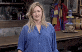 a woman in a blue polka dot shirt is standing in front of a bar