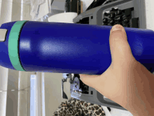 a person holding a blue water bottle with a green band