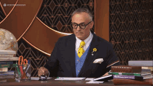 a man in a suit sits at a desk in front of a stack of books including one that says math