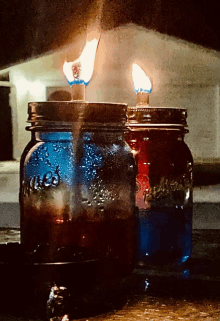 two mason jars with red white and blue liquid in them are lit up