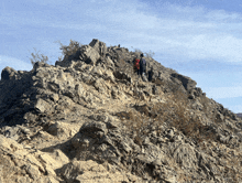 a couple of people walking up a rocky mountain