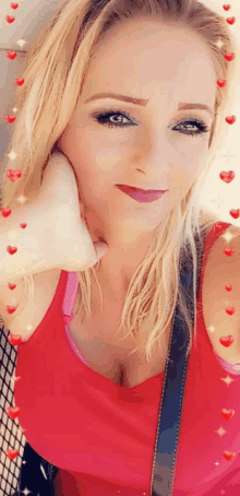 a woman in a red tank top has her hand on her chin