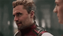 a man in a superhero costume is talking to another man in a room .
