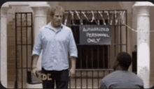 a man standing in front of a fence with a sign that says authorized personnel only