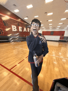 a boy holding a water bottle in front of a bears wall