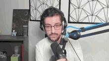 a man wearing headphones and glasses is sitting in front of a microphone .