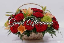 a basket filled with red roses and lilies with the words `` good afternoon '' written above it .