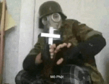 a man wearing a gas mask is holding a cross in his hand .