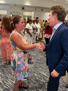 a man in a suit shakes hands with a woman in a dress