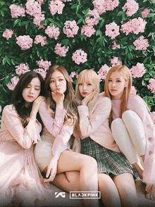 a group of girls posing in front of a wall of pink flowers with the word blackpink on the bottom