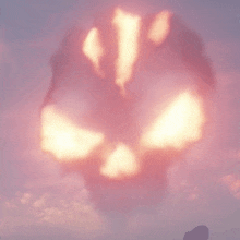 a person is standing in front of a large explosion that looks like a pumpkin .