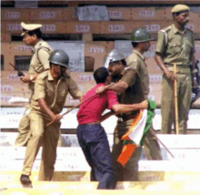 a group of police officers are holding a man with a flag in his hand