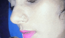 a close up of a woman 's face with a nose ring and pink lips .