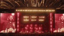 a man playing a guitar on a stage with fireworks behind him and a sign that says ' stagemagic ' on it