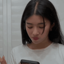 a woman with long black hair is looking at her phone .