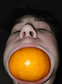 a person with an orange in their mouth