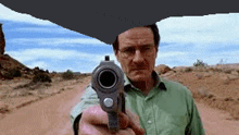 a man in a green shirt is pointing a gun at something .