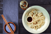 a bowl of dumplings with sauce and chopsticks on a table