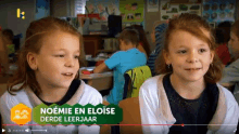 two little girls are sitting next to each other in a classroom with a green sign that says noeme en eloise