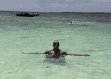 a man in sunglasses is swimming in the ocean with his arms outstretched