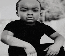 a black and white photo of a young boy in a black t-shirt