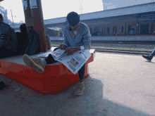 a man sits on a bench reading a newspaper which says metro