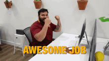 a man sitting at a desk with his fist in the air and the words awesome job written above him