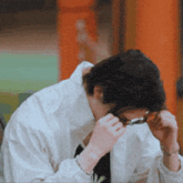 a man wearing glasses and a white shirt is looking down