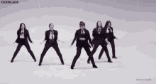 a group of women in tuxedos are dancing in a row