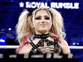 a woman in a wrestling ring with the word royal rumble behind her