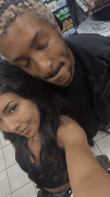 a man and a woman are posing for a selfie in front of a vending machine that sells oreos