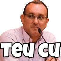 a man wearing glasses is speaking into a microphone with the words teu cu written above him