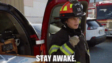 a firefighter is standing in front of a fire truck with the words `` stay awake '' written on it .