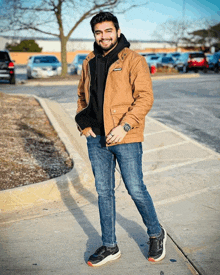 a man wearing a brown jacket and a black hoodie