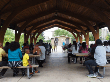 a group of people are sitting at picnic tables under a wooden roof