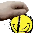 a hand is holding a yellow smiley face with a red tongue out .