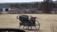 a horse drawn carriage sits in the middle of a dry grass field