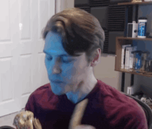 a man in a red shirt is eating a hamburger