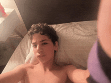 a shirtless young man laying on a bed