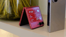 a red flip phone with the time of 17:25 on the screen
