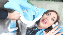 a woman with a flower in her hair is holding a cat wearing a cookie monster costume