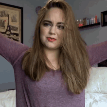 a woman with her arms outstretched is wearing a purple shirt