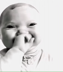 a baby is covering his mouth with his hand