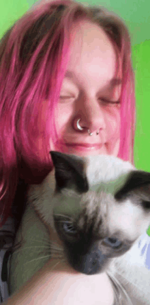 a girl with pink hair is holding a cat with her eyes closed