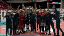 a group of volleyball players are posing for a photo with their hands in the air in front of a sign that says na żywo