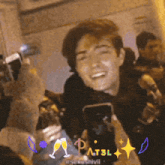 a man is holding a cell phone in front of a crowd and the word pat3l is above him