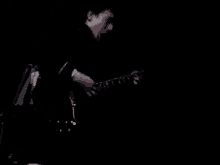 a man is playing a guitar in the dark in a dark room .