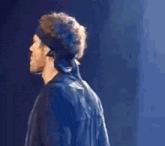 a man wearing a headband is standing on a stage and looking down .