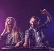 a man and a woman are standing next to each other in front of a dj booth .