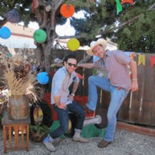 two men in cowboy hats are posing for a picture in front of a tree .